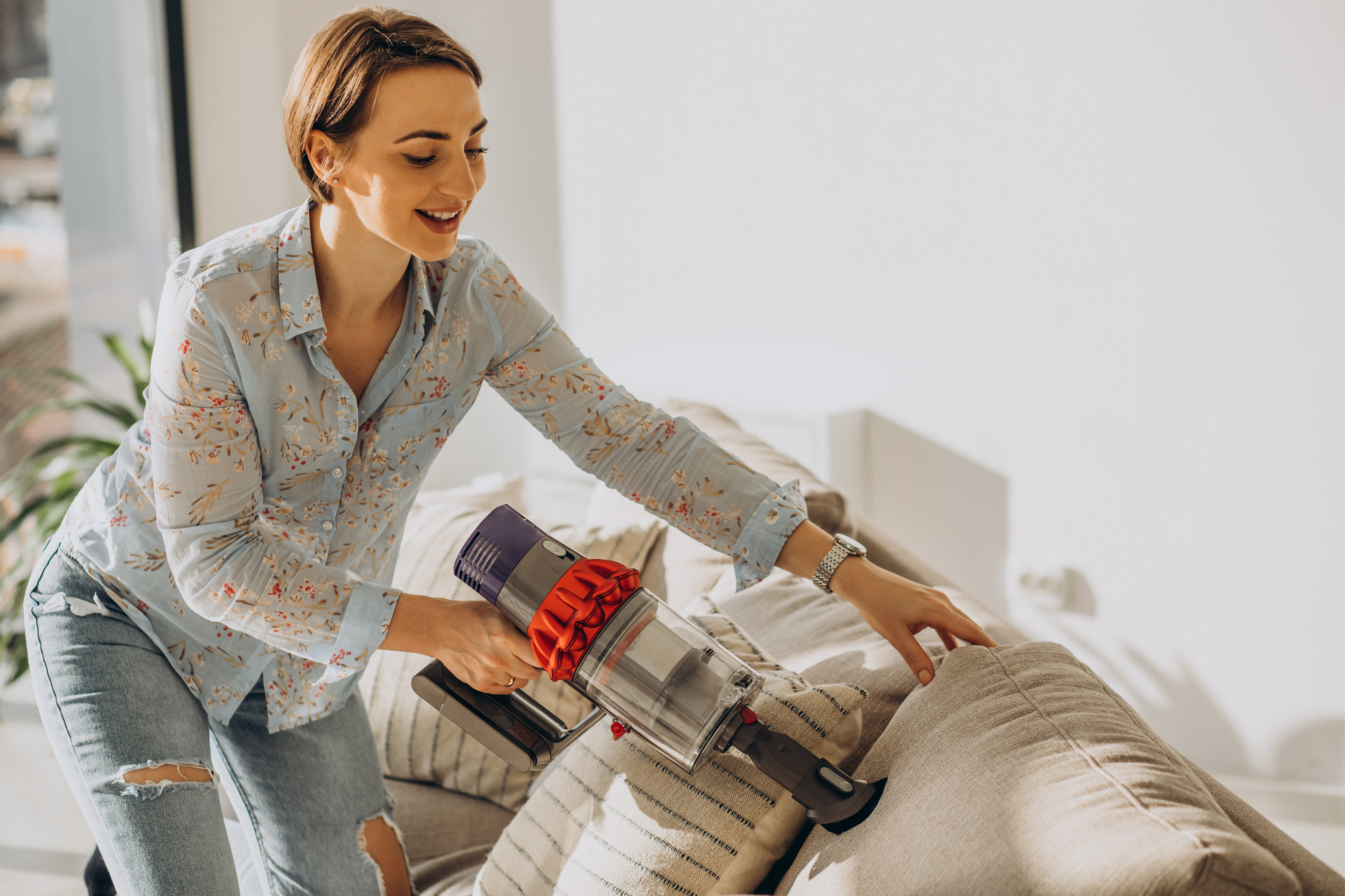 Woman vacuuming a sofa with a cordless vacuum