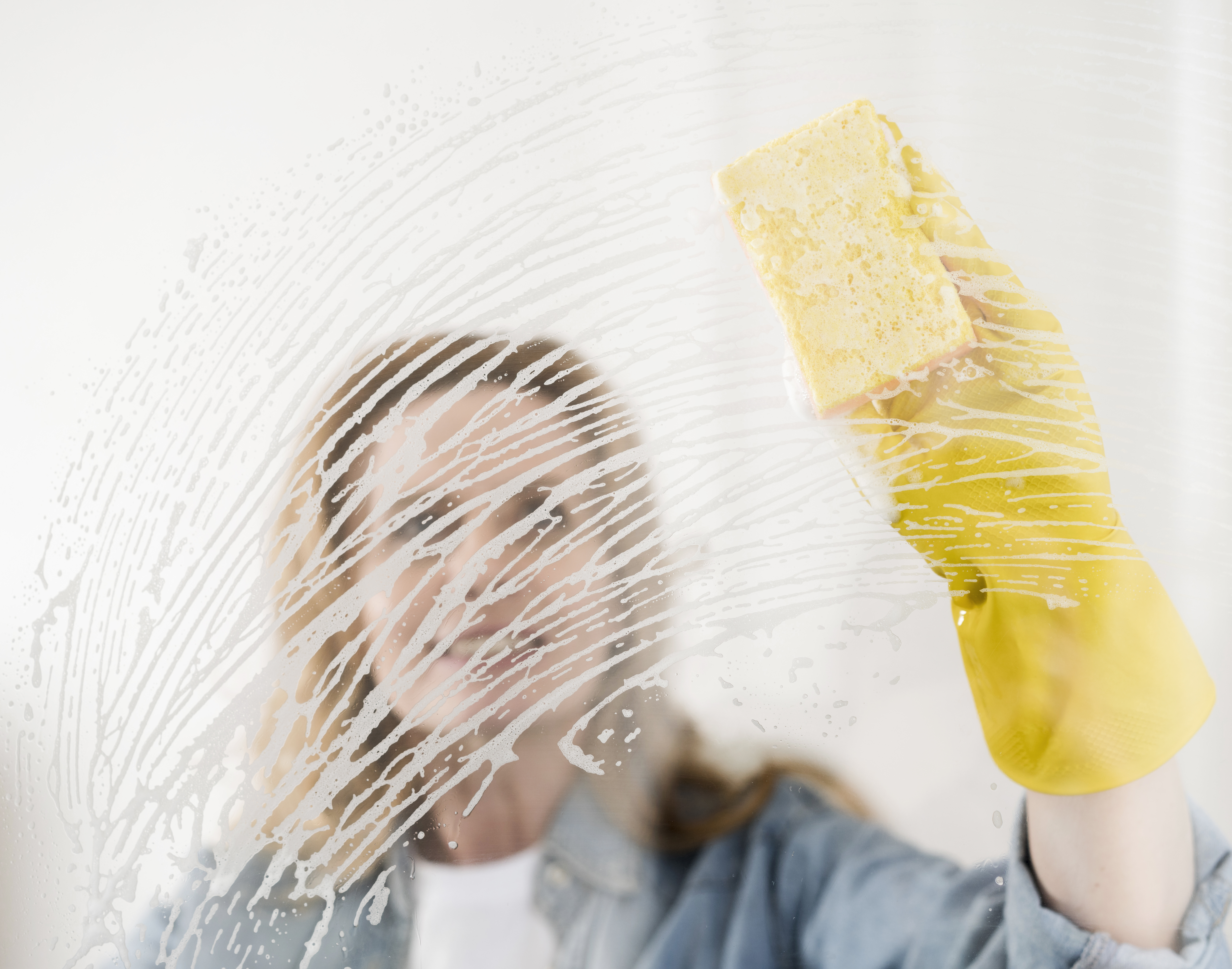 Gloved hand wiping soap off a glass window