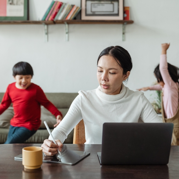 Mother working at a laptop while her children play