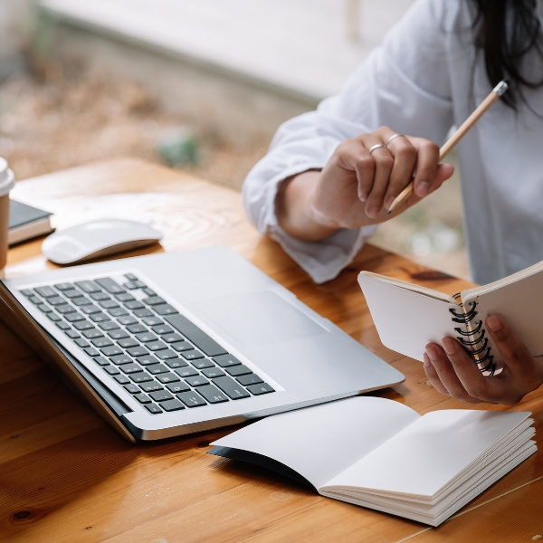 Woman writing notes next to a laptop
