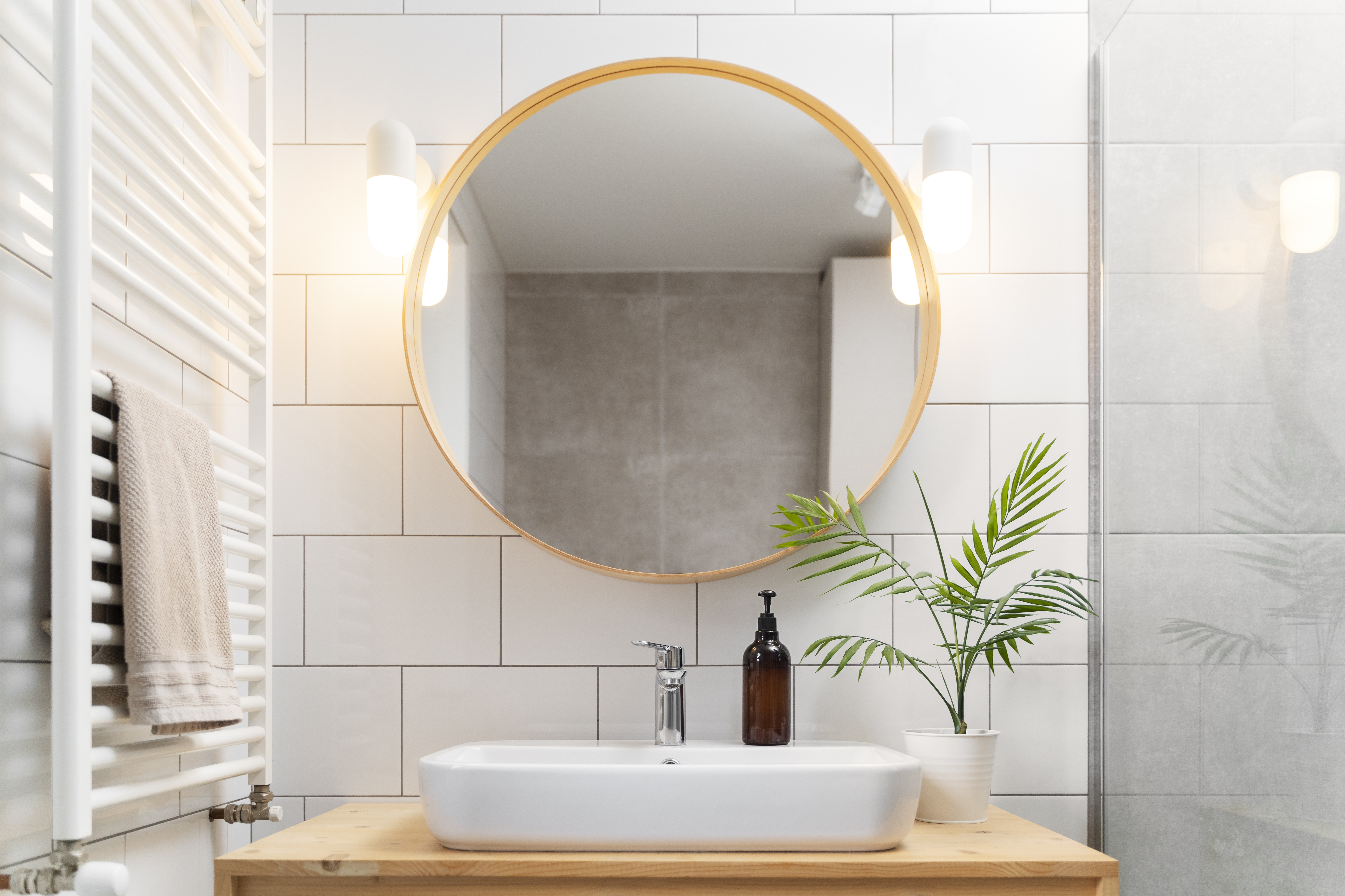 Clean bathroom with a round mirror and wooden vanity