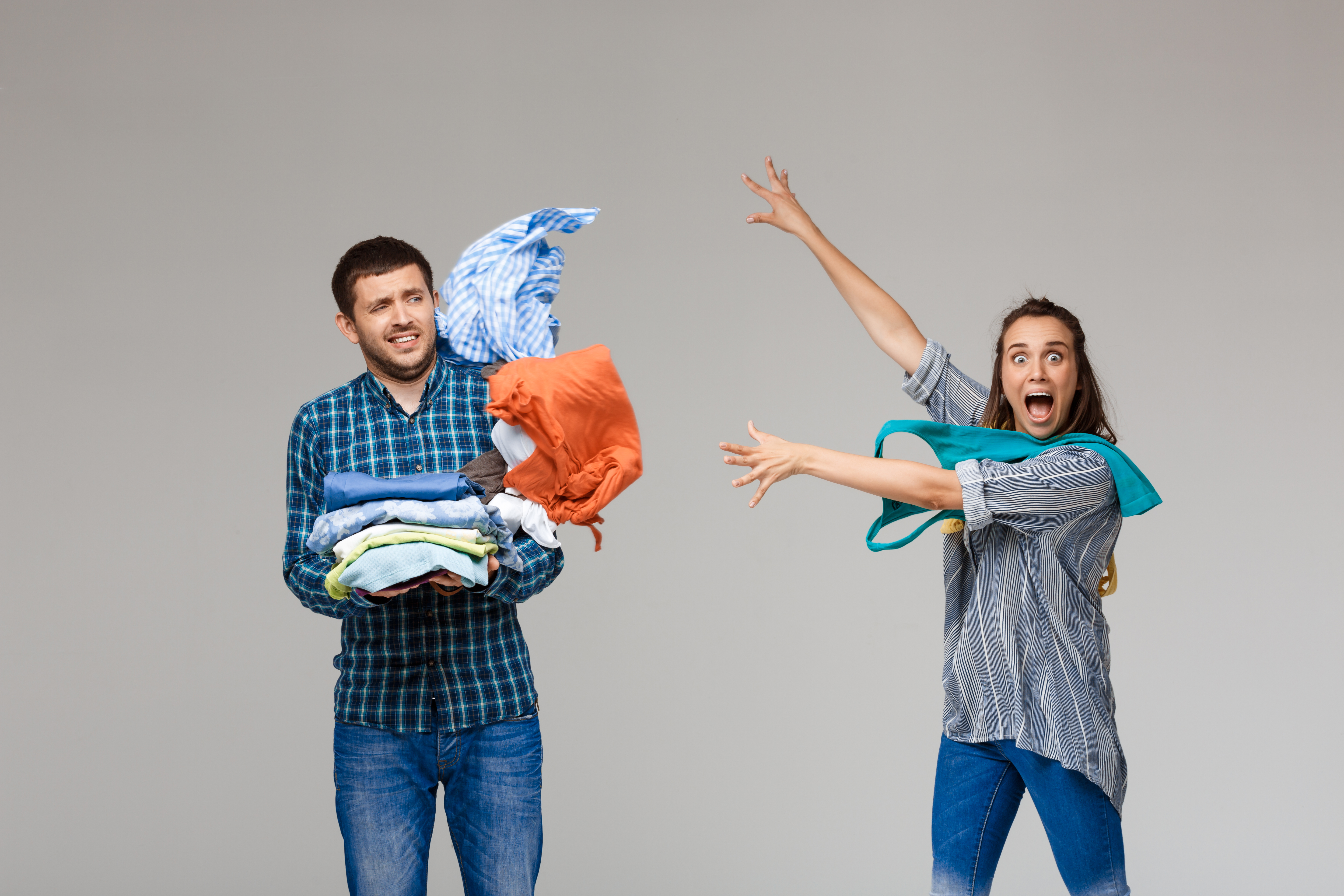 Couple holding a pile of laundry, looking overwhelmed
