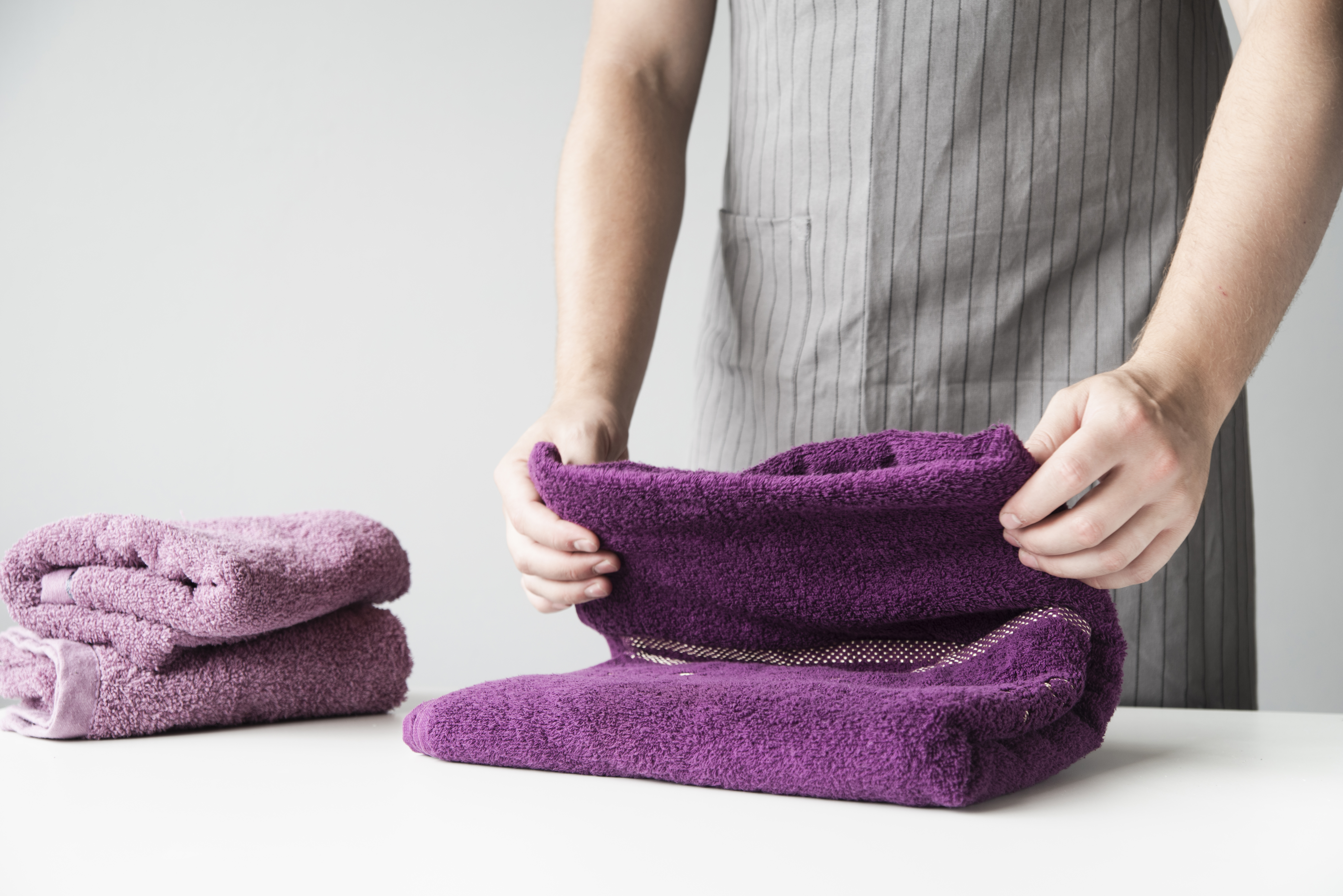 Hands folding purple microfibre towels